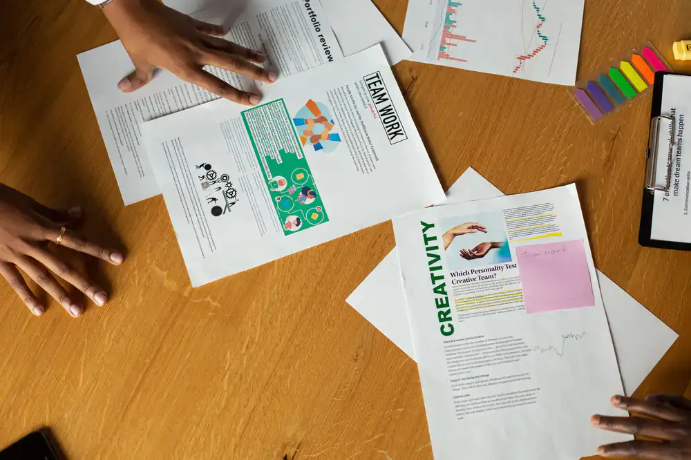 Hände prüfen verschiedene Papiersorten auf einem Holztisch